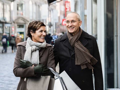 mand og en kvinde er ude på en shoppe tur på en gågade, kvinden smiler til manden og han kigger ligeud