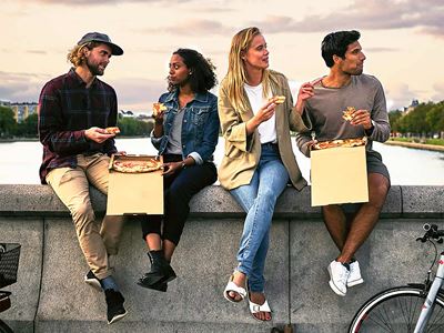 Fire unge mennesker spiser pizza