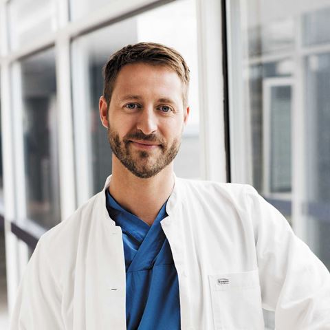 ung mand i hvid kittel smiler venligt ind i kameraret 