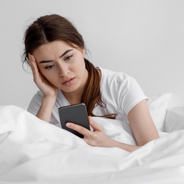 Pige ser bekymret på sin mobil