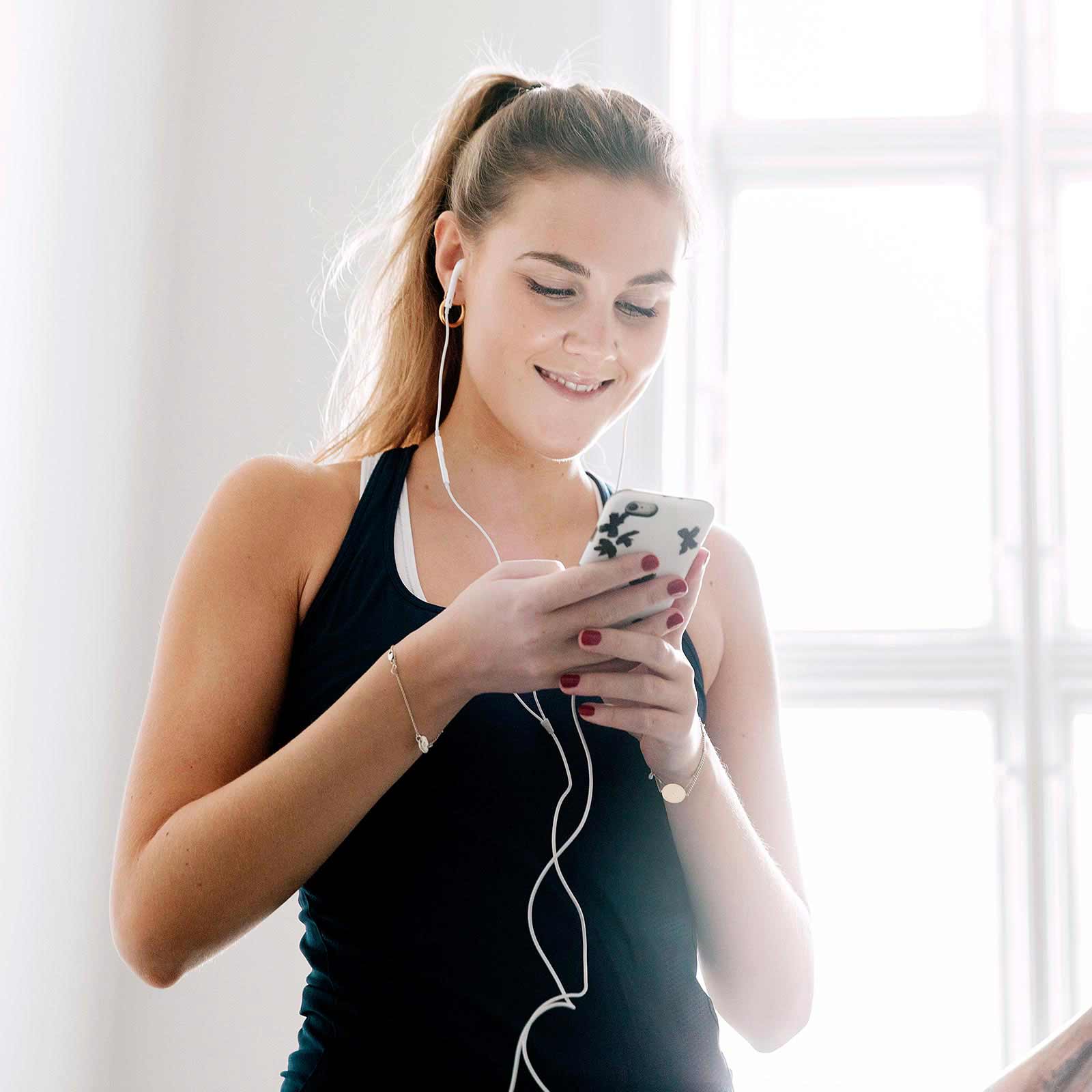 Ung kvinde lytter til musik på mobil