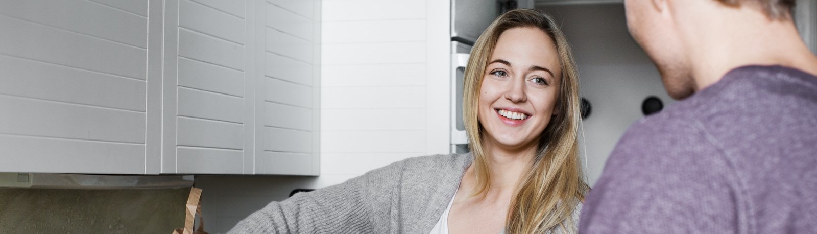 ung kvinde står i sit køkken med sine indkøbsposer