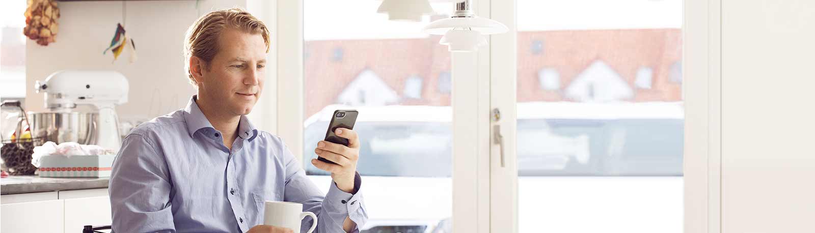 Mand sidder med sin mobil