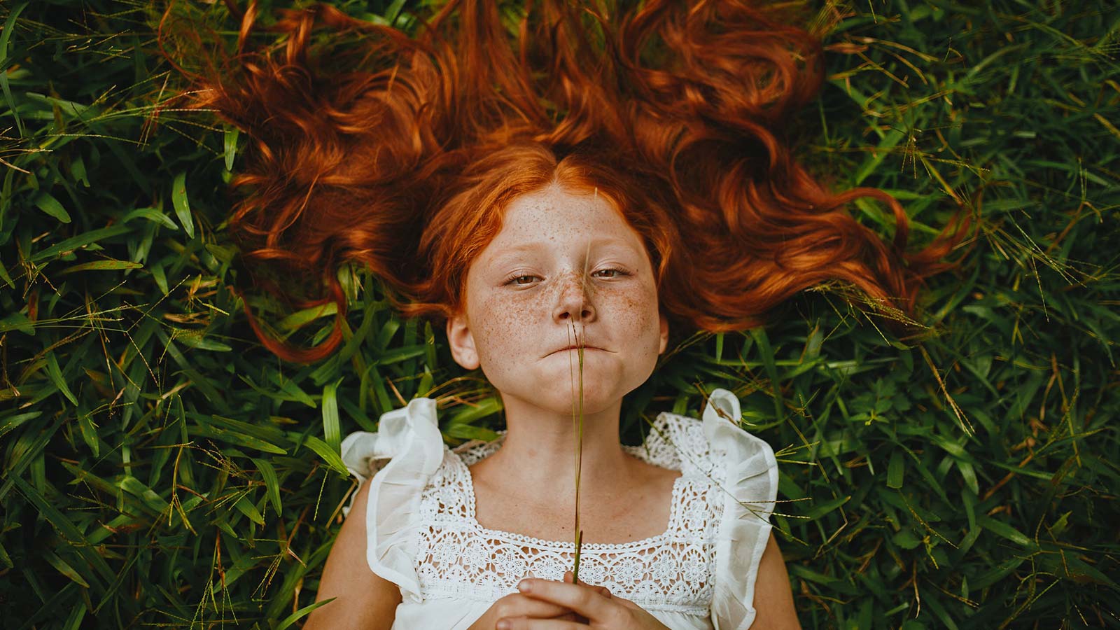 Rødhåret pige ligger i græsset