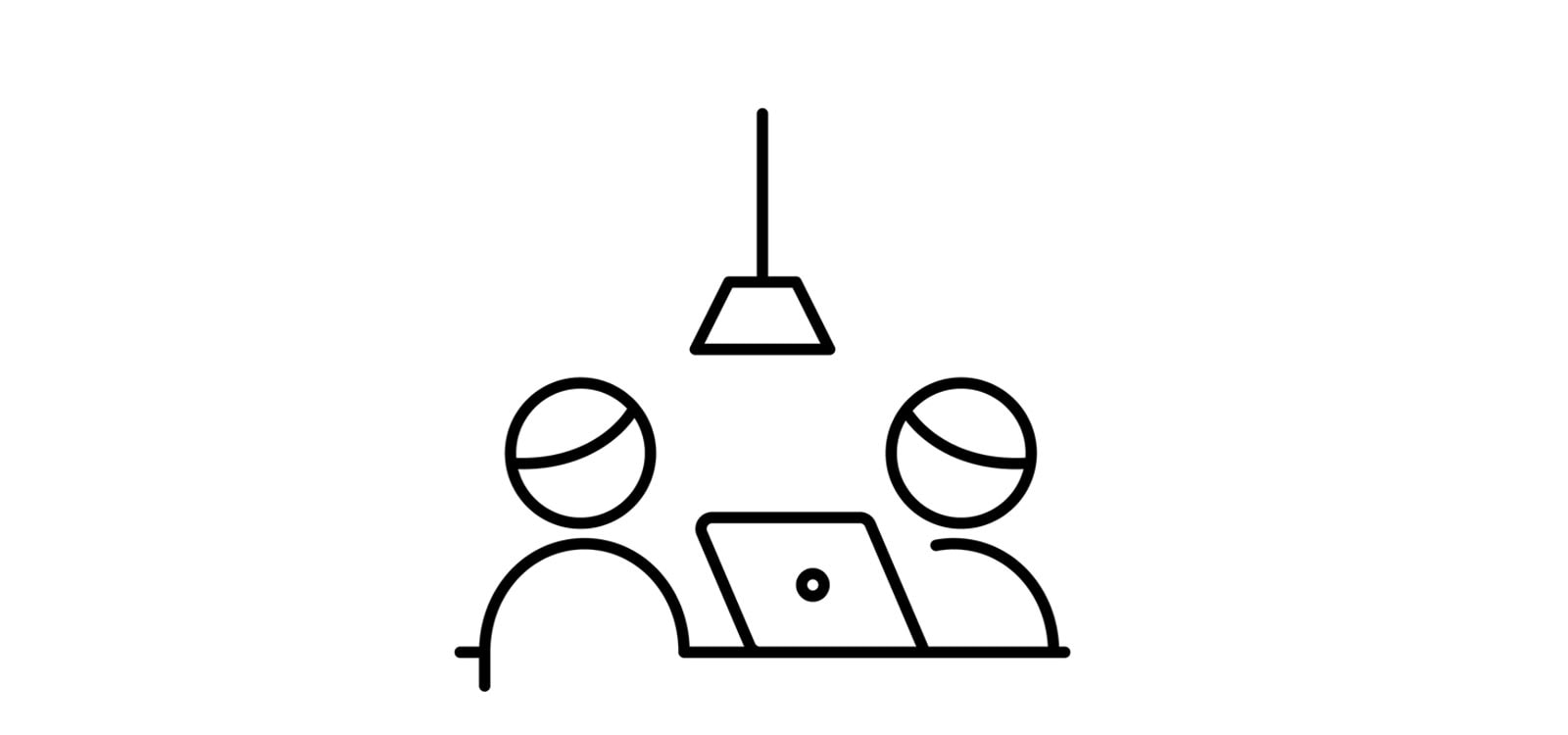 To personer der snakker over en bærbar computer ved et bord.